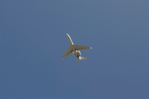 Small jet passes against blue sky