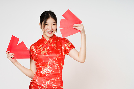 Happy Chinese new year. Asian woman holding angpao or red packet monetary gift isolated on white background.