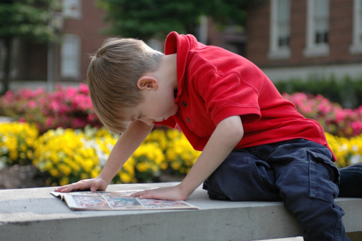 A boy reads on a bench outside of his school on a warm spring afternoon.