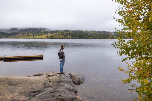 Shot in Norway, he relaxes by the lake, autumn colours in the surrounding forest