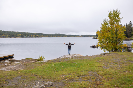 Shot in Norway, he relaxes by the lake, autumn colours in the surrounding forest