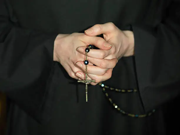 Close-up on a a nun's hands holding a rosary