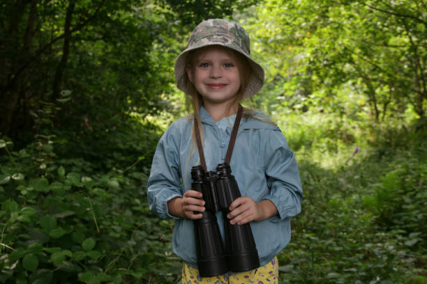 istock Cute little girl exploring nature looking through binoculars. Child playing outdoors. Kids travel, adventure and bird watching concept. 1729140210