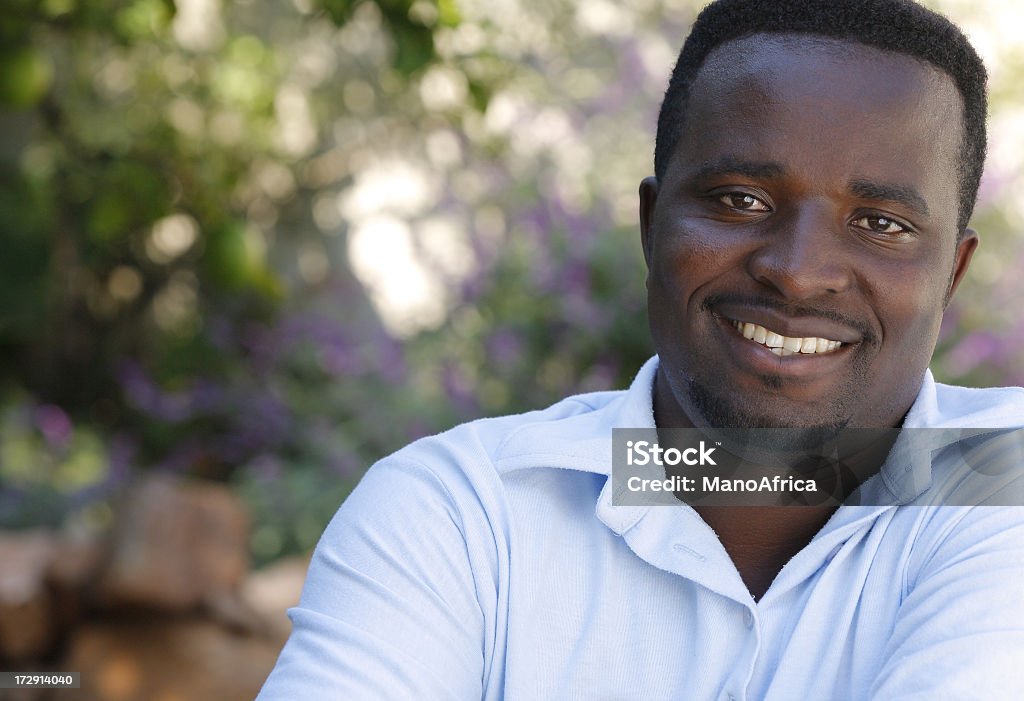 A man happy and relaxed outside A handsome young African man relaxing outside in the garden. Adult Stock Photo