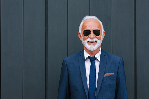 A portrait of a smiling Caucasian entrepreneur standing against blue background.