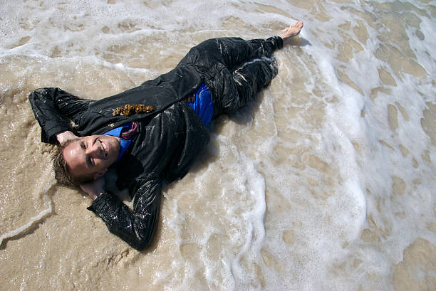 uomo d'affari sorridente in tuta con onde si - stranded beached beach businessman foto e immagini stock