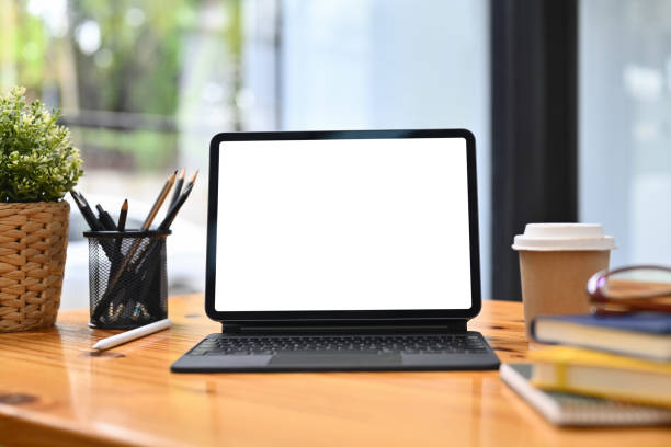 istock Front view digital tablet, pencil holder, coffee cup and book on wooden table. White screen for advertising 1729153803