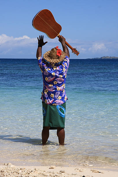 Farewell gesture "Fijian professional musician and receptionist to a Fiji island resort, in typical clothes, raises his arms in a farewell gesture at the edge of the South pacific ocean." singer back stock pictures, royalty-free photos & images