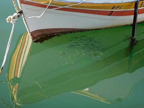 A school of fish under a fishing boat reflection