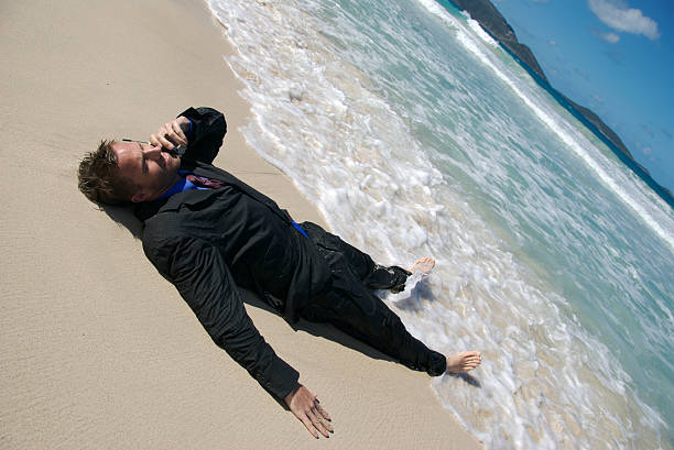joven empresario reclinables en la playa hablar con teléfono móvil - stranded men telephone beach fotografías e imágenes de stock