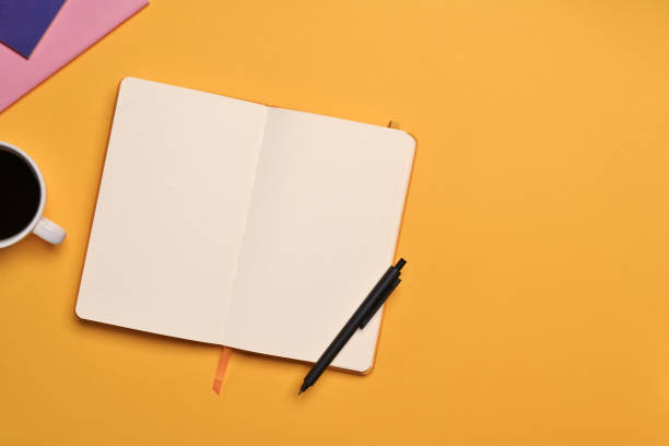 istock Blank open notebook, pen and cup of coffee on yellow background. Top view with space for text 1729167755