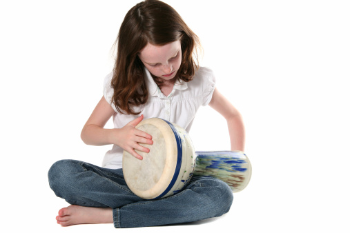 Young girl playing a djembe on a white background