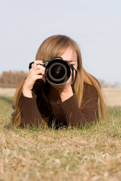 istock Female Photographer Outdoors Lying on Ground Holding SLR Camera 172916988