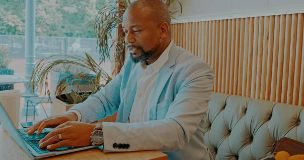 istock Laptop, cafe and professional black man typing email communication, small business feedback or cafeteria review. Remote work, morning diner and African customer reading report, project or information 1729169891