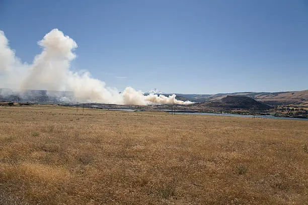 "Grassland and pasture burn on the Oregon side of the Columbia River.Mount Hood, a volcano and part of the Cascade Mountain Range is in the center of the photo between puffs of smoke.The area of the fire is The Dalles and it was taken July 16, 2008."