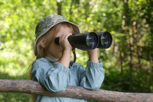 istock Cute little girl exploring nature looking through binoculars. Child playing outdoors. Kids travel, adventure and bird watching concept. 1729172729