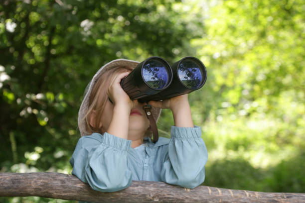 istock Cute little girl exploring nature looking through binoculars. Child playing outdoors. Kids travel, adventure and bird watching concept. 1729172730
