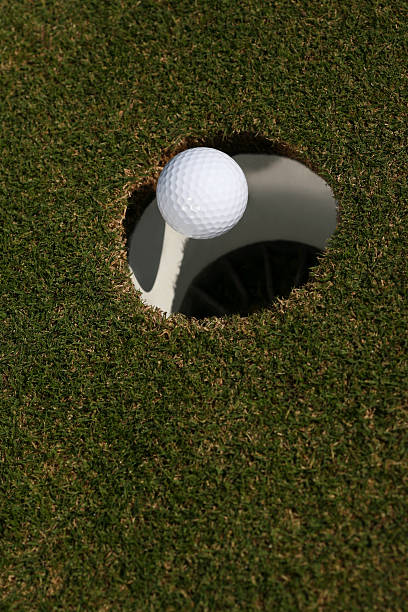 golf ball falling into the hole from an inside the cup perspective. final moment of a perfect putt, precision, success, and achievement in the sport concept.