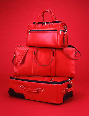 Three pieces of matching luggage on a red back ground