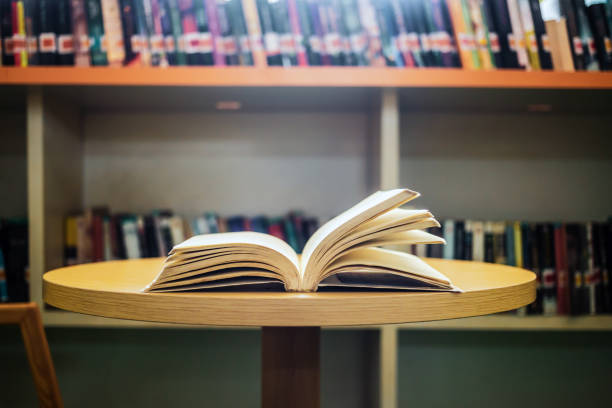 istock Vintage style.An open book or textbook vintage style in the library with light from the window on the reading table and the corridor of the bookshelves in the school classroom background.Education learning concept 1729196351