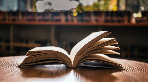 istock Vintage style.An open book or textbook vintage style in the library with light from the window on the reading table and the corridor of the bookshelves in the school classroom background.Education learning concept 1729196395