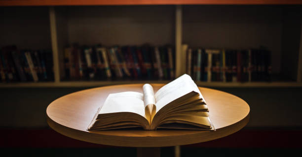 istock Vintage style.An open book or textbook vintage style in the library with light from the window on the reading table and the corridor of the bookshelves in the school classroom background.Education learning concept 1729196869