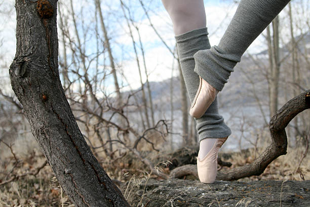 The bare feet of a woman dancer standing on concrete floor.