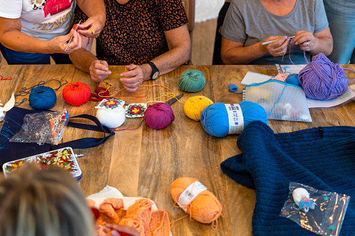 Crochet club. Ladies crocheting with colored wool.