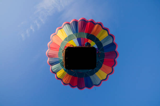 Hot air balloon rising into a blue sky stock photo