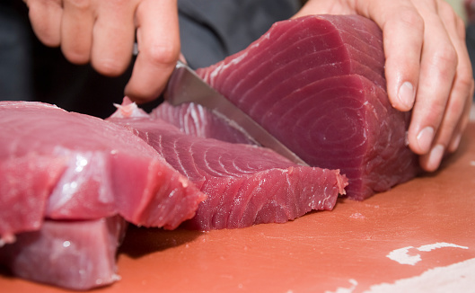 human hand cutting fresh tuna steak close-up