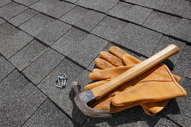 Hammer and pair of gloves and nails on rooftop stock photo