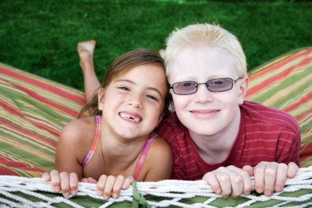 Brother and sister playing in a hammock