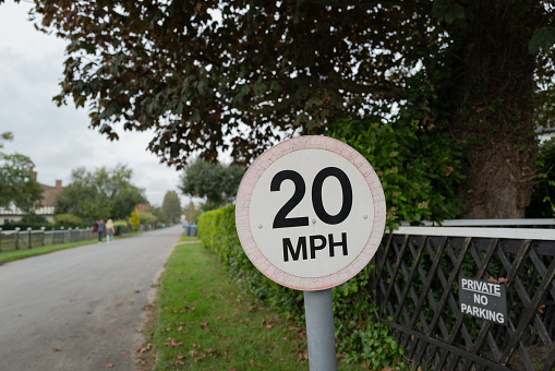 Shallow focus of a weathered 20 mph speed limited sign seen at the entrance to a private road with a housing estate located on the Suffolk coast.