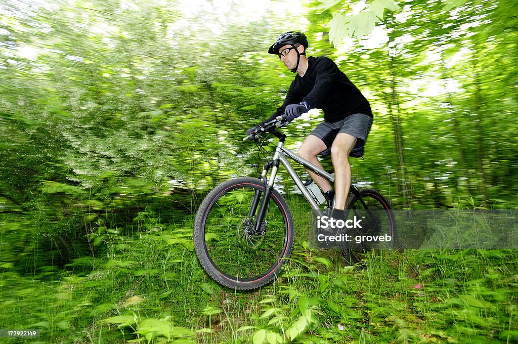 O Mountain biker em um salto na floresta. - Foto de stock de Artigo de vestuário para cabeça royalty-free