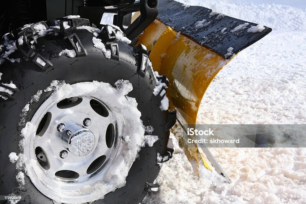 Plowing Snow with Blade Mounted on an ATV Plowing snow with a blade mounted on the rear of four-wheeler (ATV).  Close up. Snowplow Stock Photo