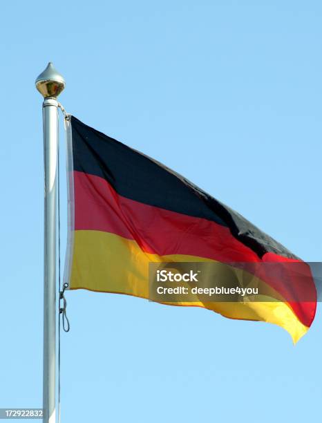 A German Flag Waving In The Wind Set On A Clear Blue Sky Stock Photo - Download Image Now