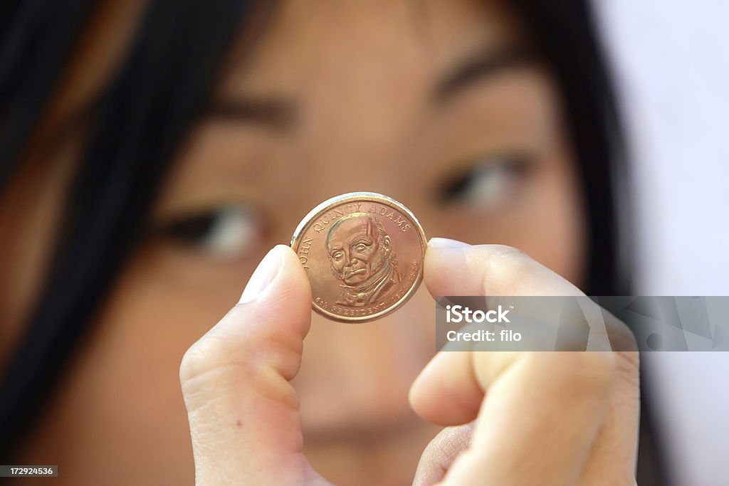 Coin Collecting A young woman looks closely at a US one dollar coin. Adult Stock Photo