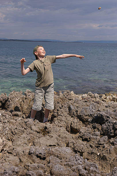 ребенка бросать камни на пляже - throwing stone human hand rock стоковые фото и изображения