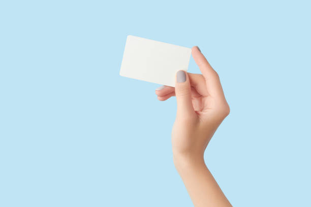 istock Manicured womans hand holding business card on grey concrete background 1729254606