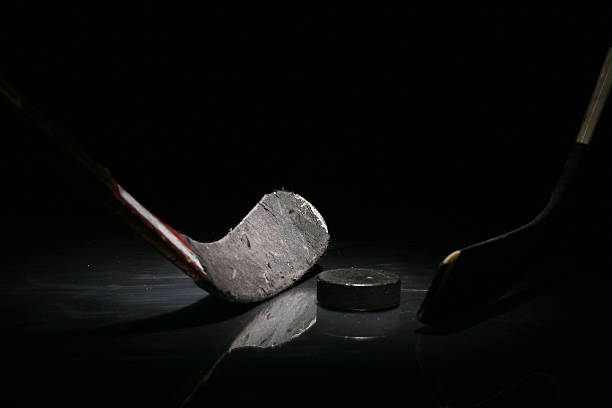A gray hockey stick and a puck in solitude More ice hockey shots - check my lightbox. hockey puck photos stock pictures, royalty-free photos & images