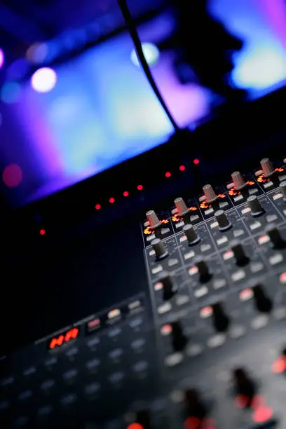 Close-up vertical shot of soundboard in recording studio.