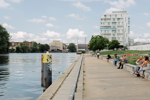 Berlin, Germany. August 23, 2022. The Spree River runs through the capital of Germany for a good part and along its course there are parks and places of leisure. In this image you can see some tourists sitting on the banks of the river in a city park