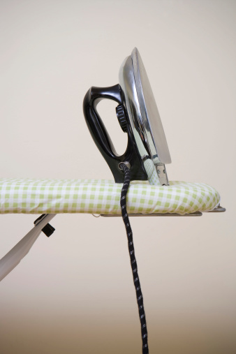 Stock photo of the side view of an iron resting on a checkered ironing board