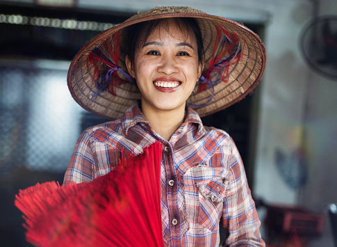 portrait of smiling vietnamese woman holding bundle of red incense sticks in her hands