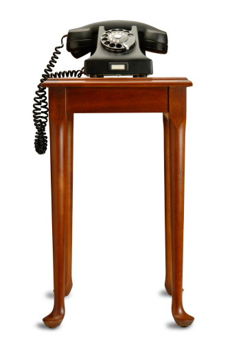 Vintage Black Phone with Small Desk on White.