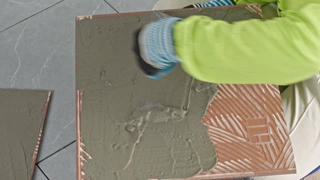 Construction worker applying cement mortar to tile