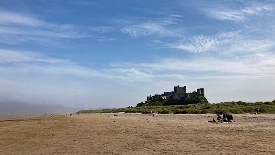 People on the beach with Bamburgh castle in the background