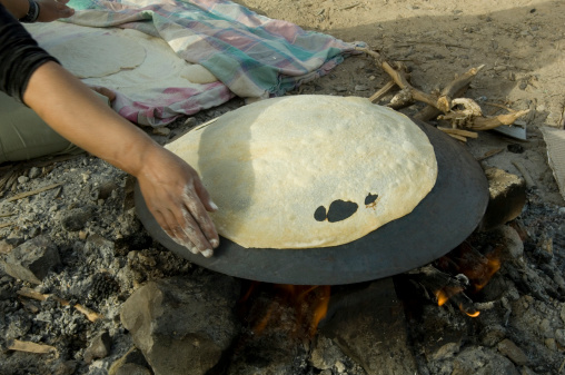 A Bedouin woman baking pita bread on a stove in the Arava desert Israel