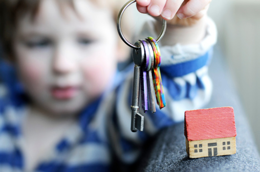 A Three year old boy with toy house and a dummy set of keys. Focus on house, small amount motion blur on keys.
