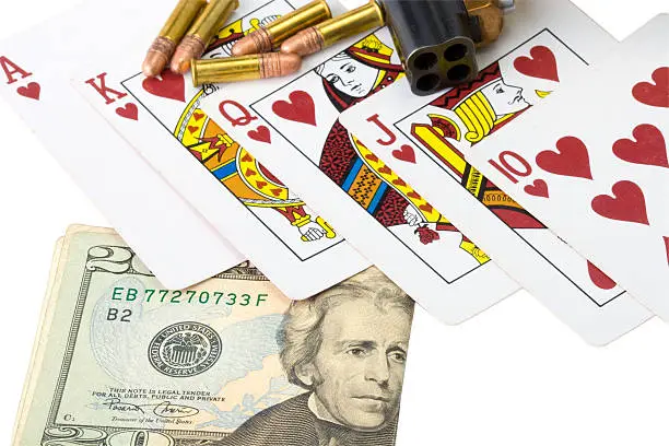 Photo of Closeup of cards, money, derringer handgun and bullets